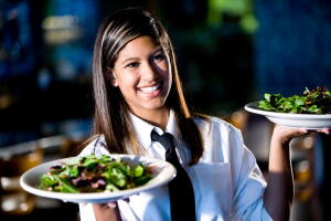 Happy friendly hispanic waitress serving salads