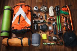 climbing equipment: rope, trekking shoes, crampons, ice tools, ice ax, ice screws, set on dark wooden background, top view.