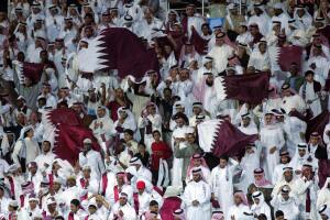 Qatari fans wave national flags as they