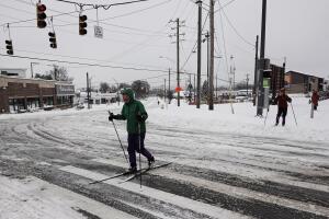 Un hombre cruza una calle mientras practica esquí de fondo en Cincinnati.