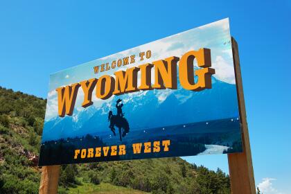 07/13/2015 - Newcastle, Wyoming, USA: Welcome to Wyoming sign with text "Forever West" and horse with cowboy