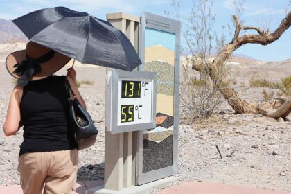 A woman stands near a digital display of an unofficial heat reading at Furnace Creek Visitor Center during a heat wave in Death Valley National Park in Death Valley, California, on July 16, 2023. Tens of millions of Americans braced for more sweltering temperatures Sunday as brutal conditions threatened to break records due to a relentless heat dome that has baked parts of the country all week. By the afternoon of July 15, 2023, California's famous Death Valley, one of the hottest places on Earth, had reached a sizzling 124F (51C), with Sunday's peak predicted to soar as high as 129F (54C). Even overnight lows there could exceed 100F (38C). (Photo by Ronda Churchill / AFP) (Photo by RONDA CHURCHILL/AFP via Getty Images)