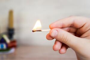 the child holds a lit match and it burns with a flame