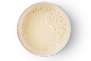 Cup with soy milk bubble foam on white background