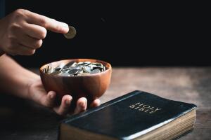 One tenth or tithe is basis on which Bible teaches us to give one tenth of first fruit to God. coins with Holy Bible. Biblical concept of Christian offering, generosity, and giving tithes in church.