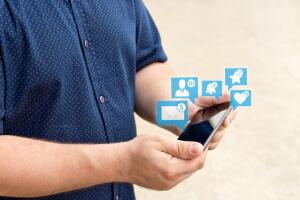 Young man holding smartphone with icons of notifications from social media. Social media concept. Chat.