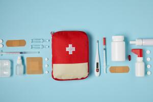 top view of red first aid kit bag on blue surface with medical supplies