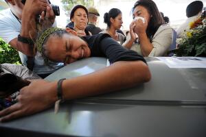 A relative cries over the coffin of one