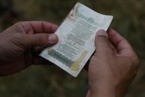 A U.S. Border Patrol agent inspects a discarded passport found at a migrant crossing spot on the Rio Grande near Mission