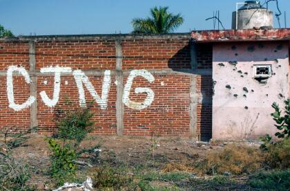 Vista de un muro acribillado a balazos con las iniciales del grupo criminal Cartel Jalisco Nueva Generación (CJNG) a la entrada de la comunidad de Aguililla, estado de Michoacán, México, el 23 de abril de 2021.