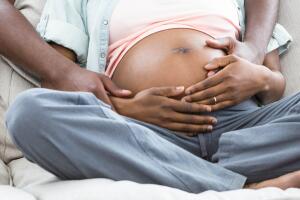 Man embracing and kissing pregnant woman from behind