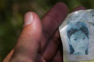 A U.S. Border Patrol agent inspects the discarded passport of a young migrant girl found at an illegal crossing spot on the Rio Grande near Mission