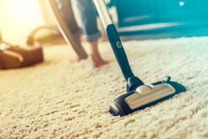 Woman using a vacuum cleaner while cleaning carpet in the house.