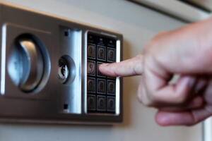 Blurred safe with combination lock and human hand in a hotel room, closeup numbers with tilt shift effect. Selective focus
