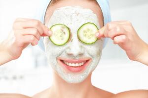 Funny young girl with a mask for skin face and cucumbers