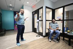Andres Acosta Ardila (izq.), director de relaciones comunitarias de Pineapple Healthcare, saluda a Fernando Hermida mientras espera su cita en la clínica médica de Orlando, Florida, el 28 de mayo de 2024.