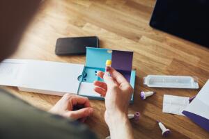 Home blood DNA COVID-19 test with man holding test tube sample.