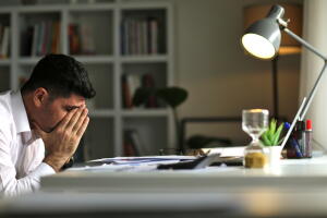 Tired young businessman working at home using lap top and looking Anxious