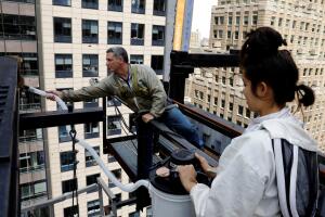 Beekeeper Andrew Cote works with Hannah Baek to use a specialized vacuum cleaner to remove a large swarm of bees that had taken up residence on a building in the Times Square district of New York