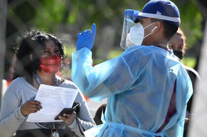 A healthcare worker speaks to a woman at a walk-up Covid-19 testing site, November 24, 2020, in San Fernando, California, just northeast of the city of Los Angeles. - California shattered the state's single-day COVID-19 record with over 20,500 new cases recorded on November 23 ahead of the Thanksgiving holiday. (Photo by Robyn Beck / AFP) (Photo by ROBYN BECK/AFP via Getty Images)