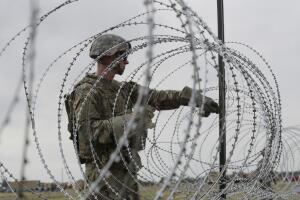 Soldados en ropa de combate siguen colocando alambres de púas a lo largo de la frontera con México.